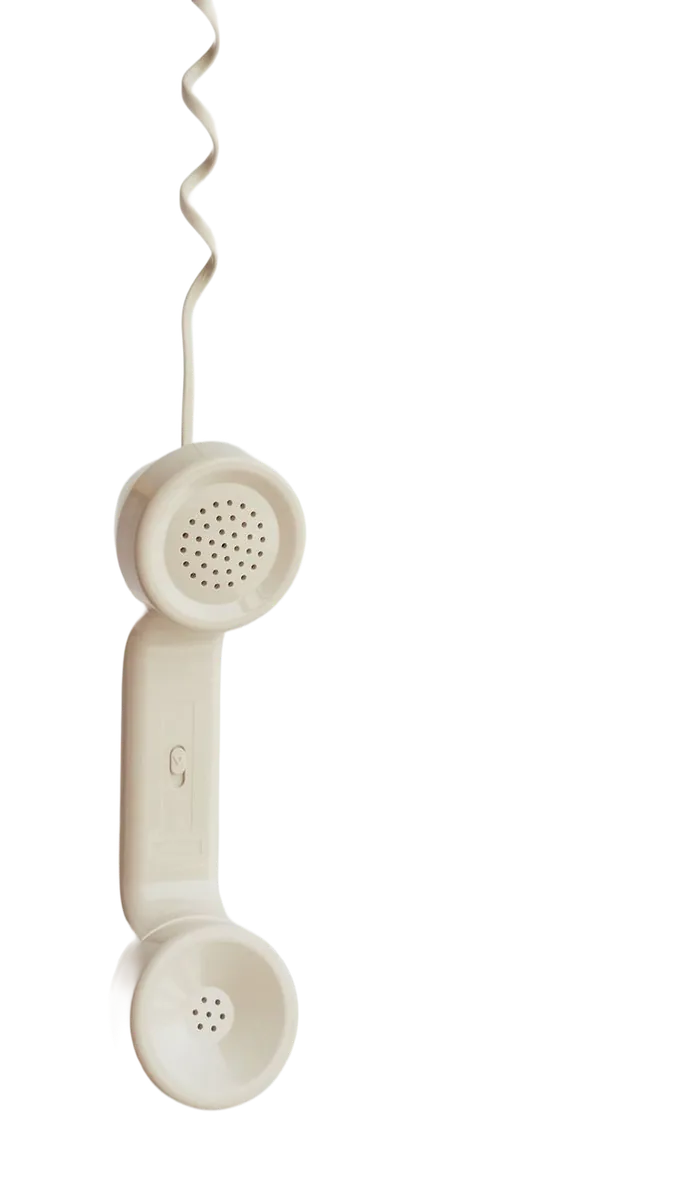 A cream desk phone handset hanging from its coiled cord.